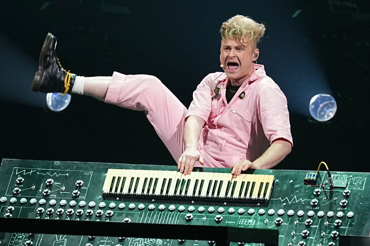 A keyboardist kicks out their leg during a performance.