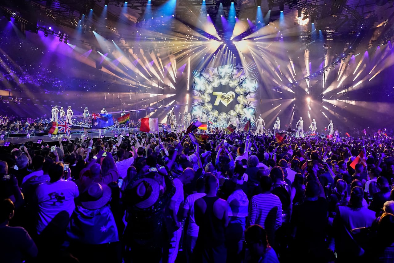 Performers are seen onstage as audience members look on.