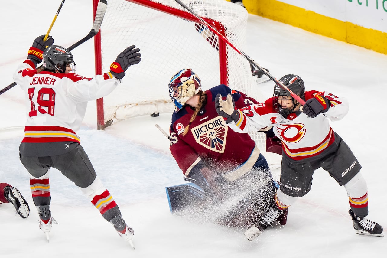 Two hockey players celebrate as the puck is shown in the back of the opposing team's net.