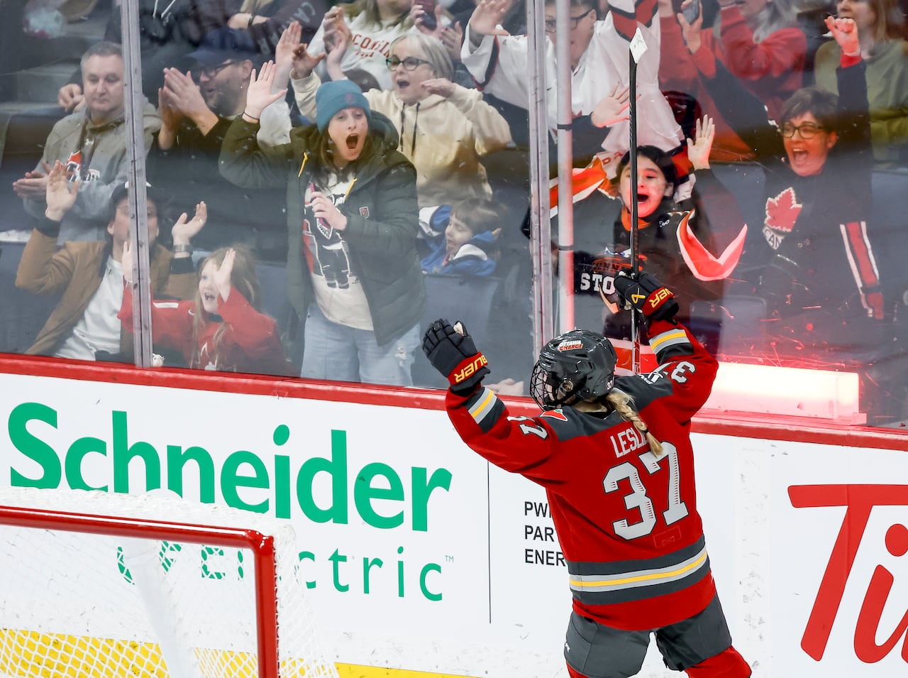A hockey player celebrates on the ice, facing the crowd through the glass.