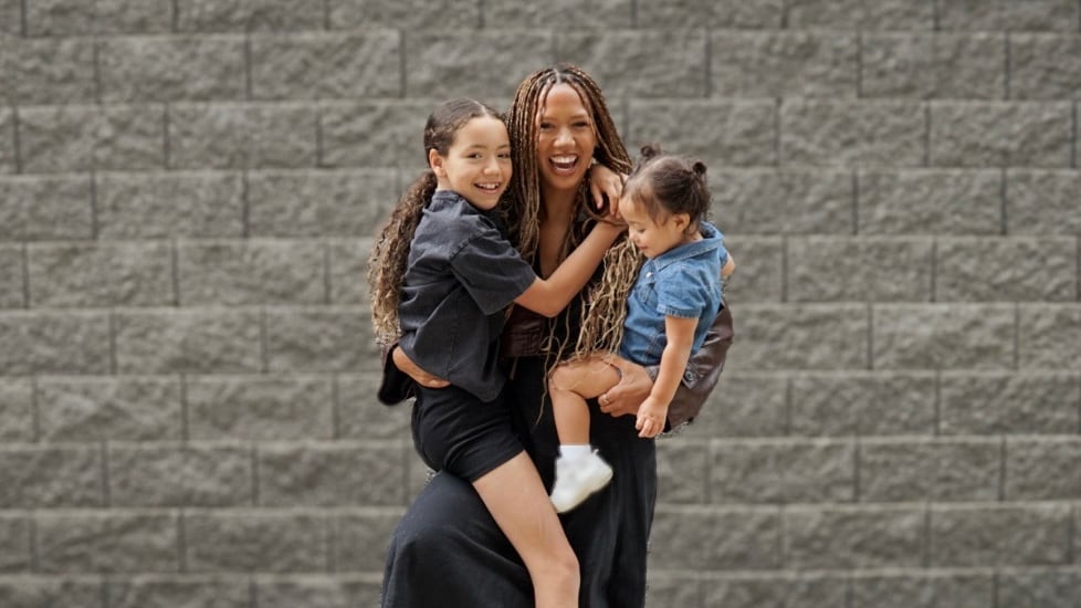 A mother smiles while holding her two children