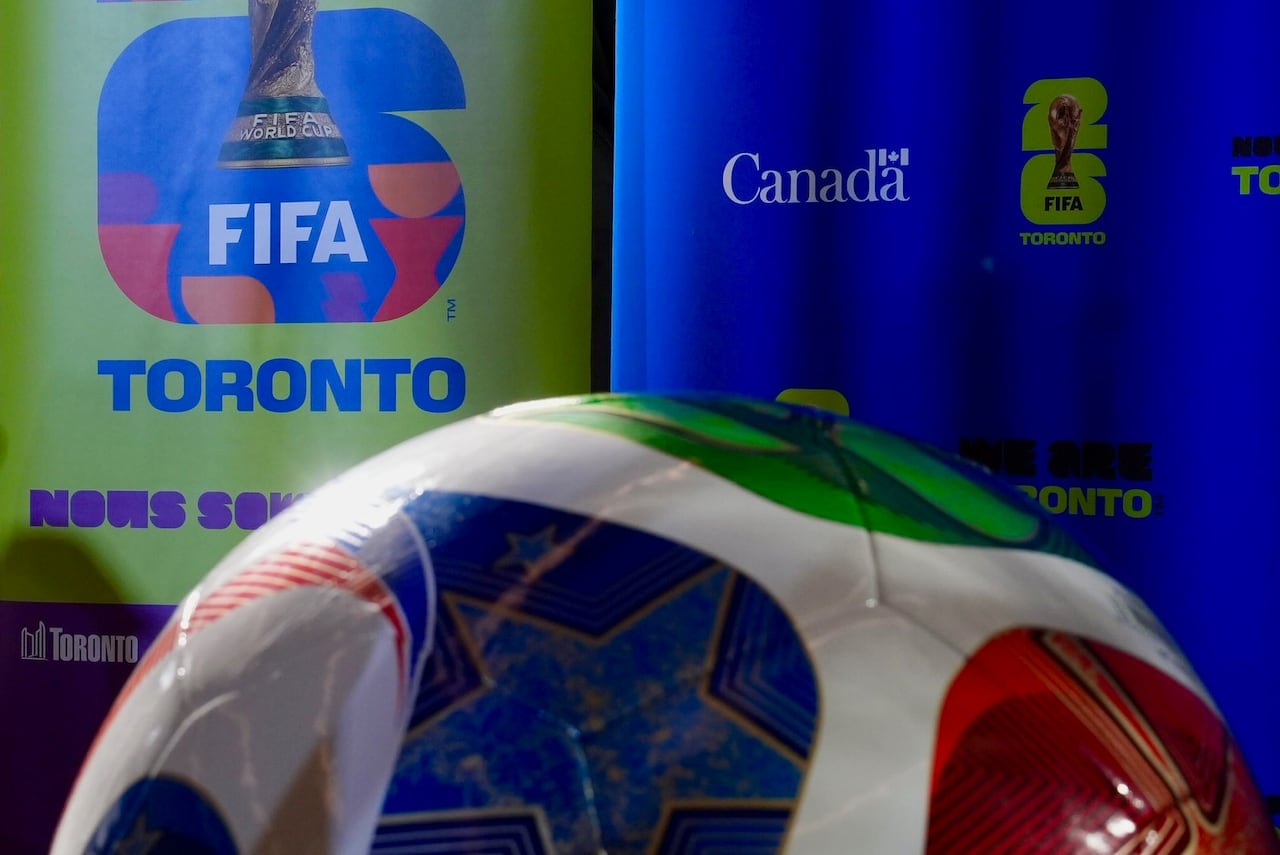A soccer ball is on display in the foreground in a room decked out with Toronto FIFA signage