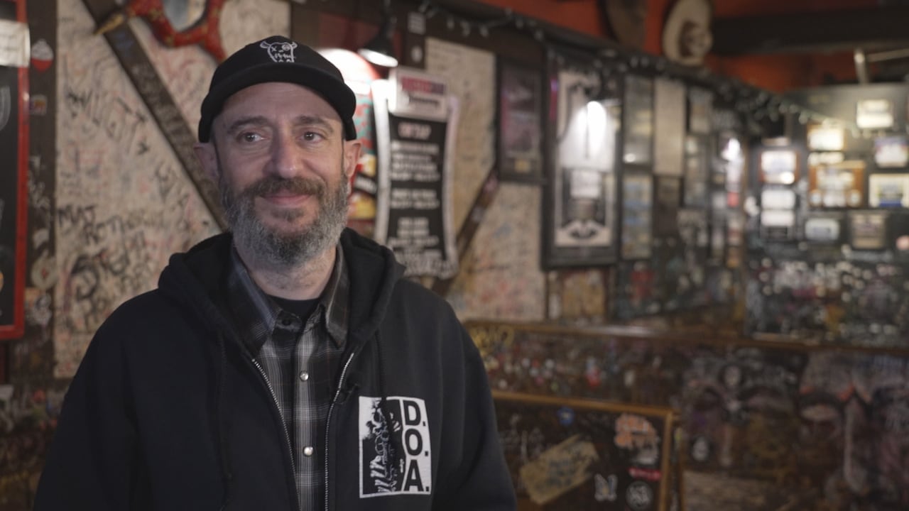 A man stands in a Toronto bar, smiling at the camera.