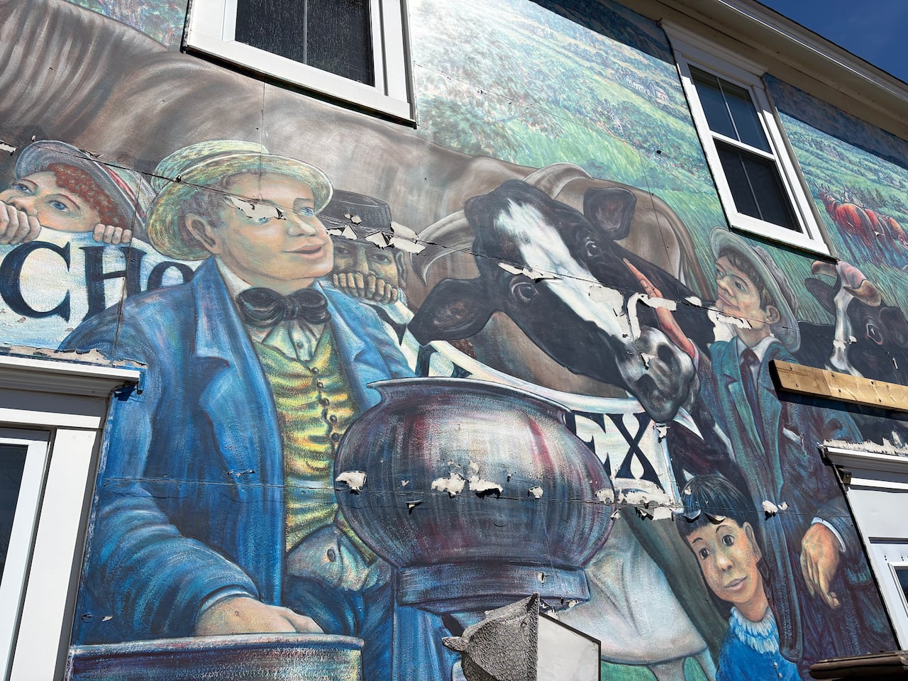 A faded mural of a boy and a cow, with paint peeling all over.