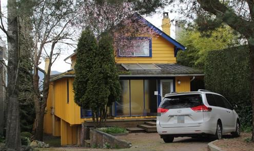 A large yellow house is seen with multiple levels.