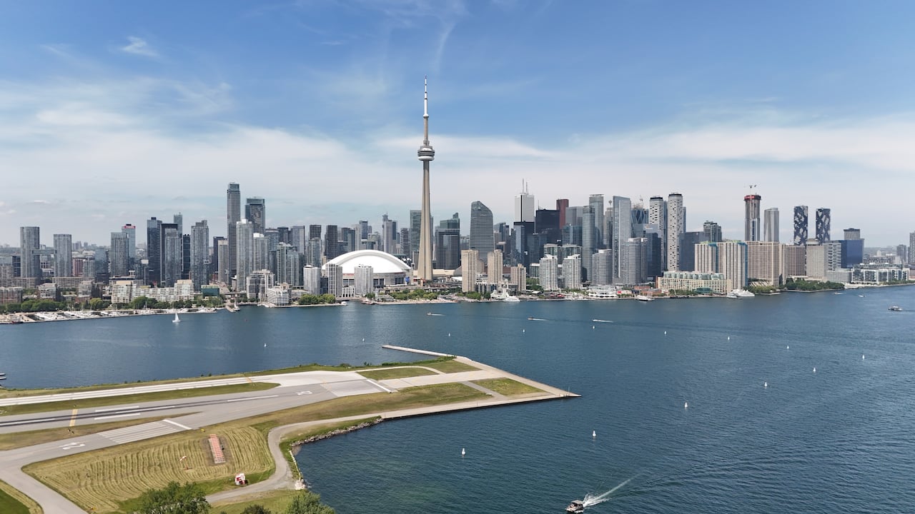 Drone image of runway at Billy Bishop airport, with a view of the Toronto skyline.