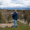 Mike Durglo Jr. stands on a hillside above a river looking towards a mountain range. Durglo has devoted his life to preparing his home and his people for climate change. As the Confederated Salish and Kootenai Tribes climate change coordinator he wrote one of the first tribal climate action plans in the country over 15 years ago.