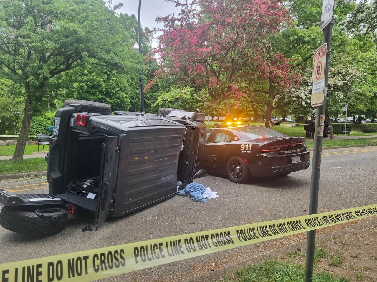 A large vehicle is flipped on its side. It appears to have crashed into a police car, in which the airbags seem to have gone off.