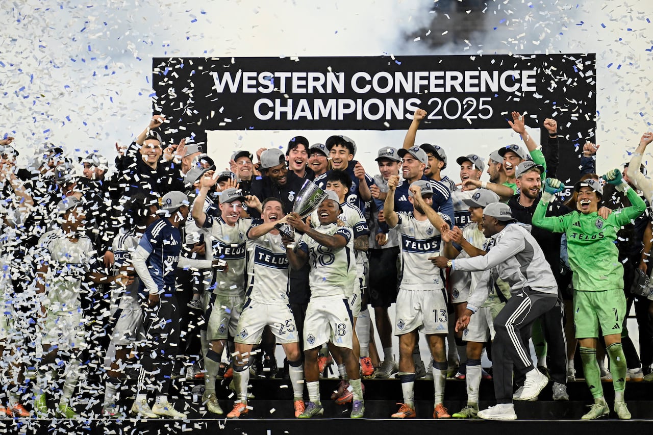 A group of soccer players celebrate amid confetti on a podium