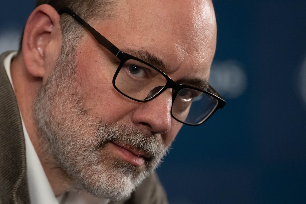 Portrait of a man with a grey beard wearing black-framed glasses.