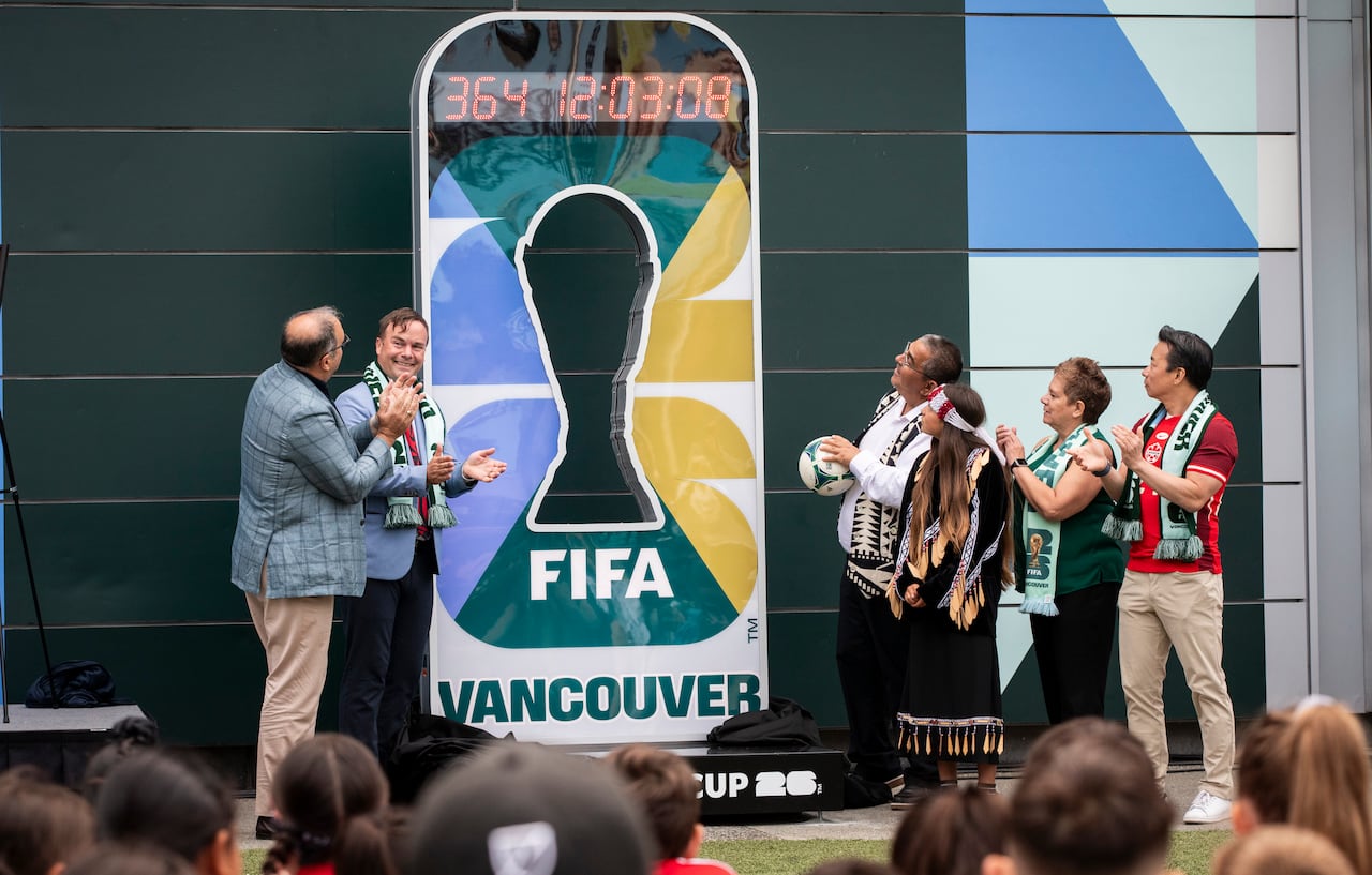 A small group of people present a clock with a one-year countdown on it.