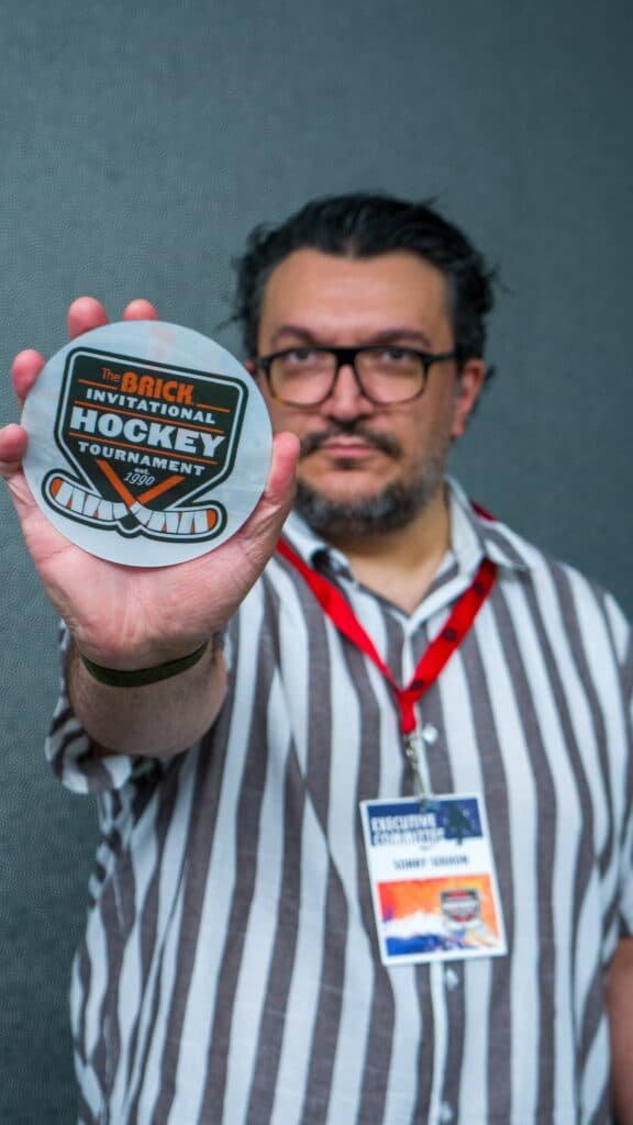 Sonny Sekhon holding a Brick Invitational Hockey Tournament disk.