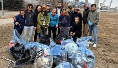A group of people stand with garbage bags in front of the Walterdale Bridge.