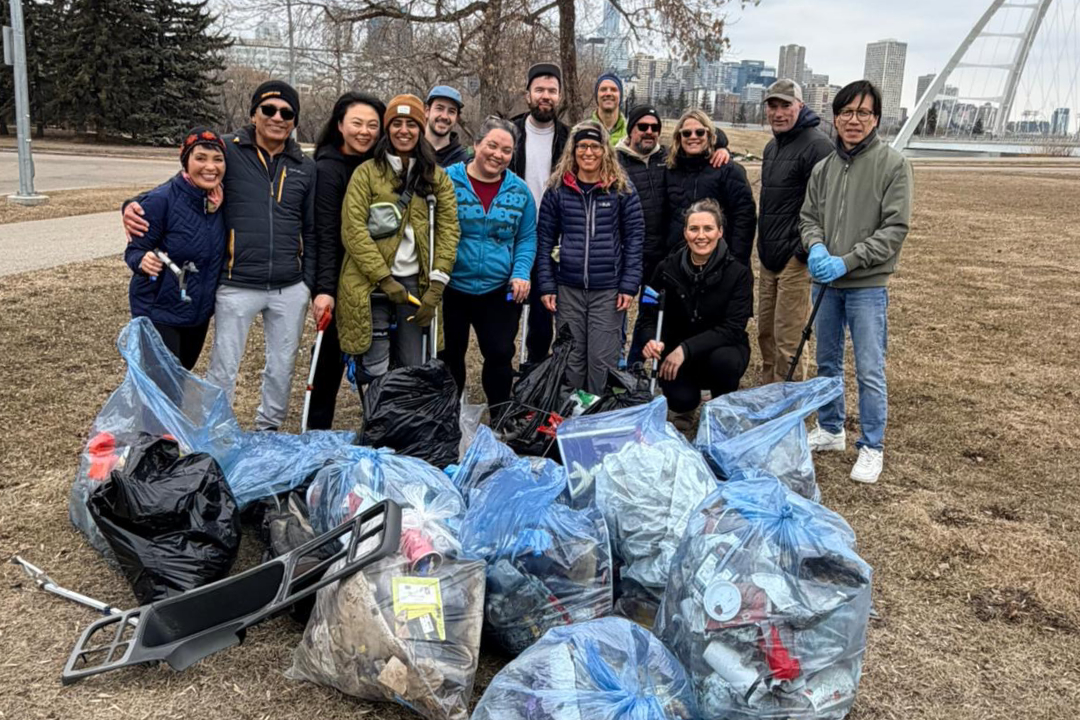 A group of people stand with garbage bags in front of the Walterdale Bridge.