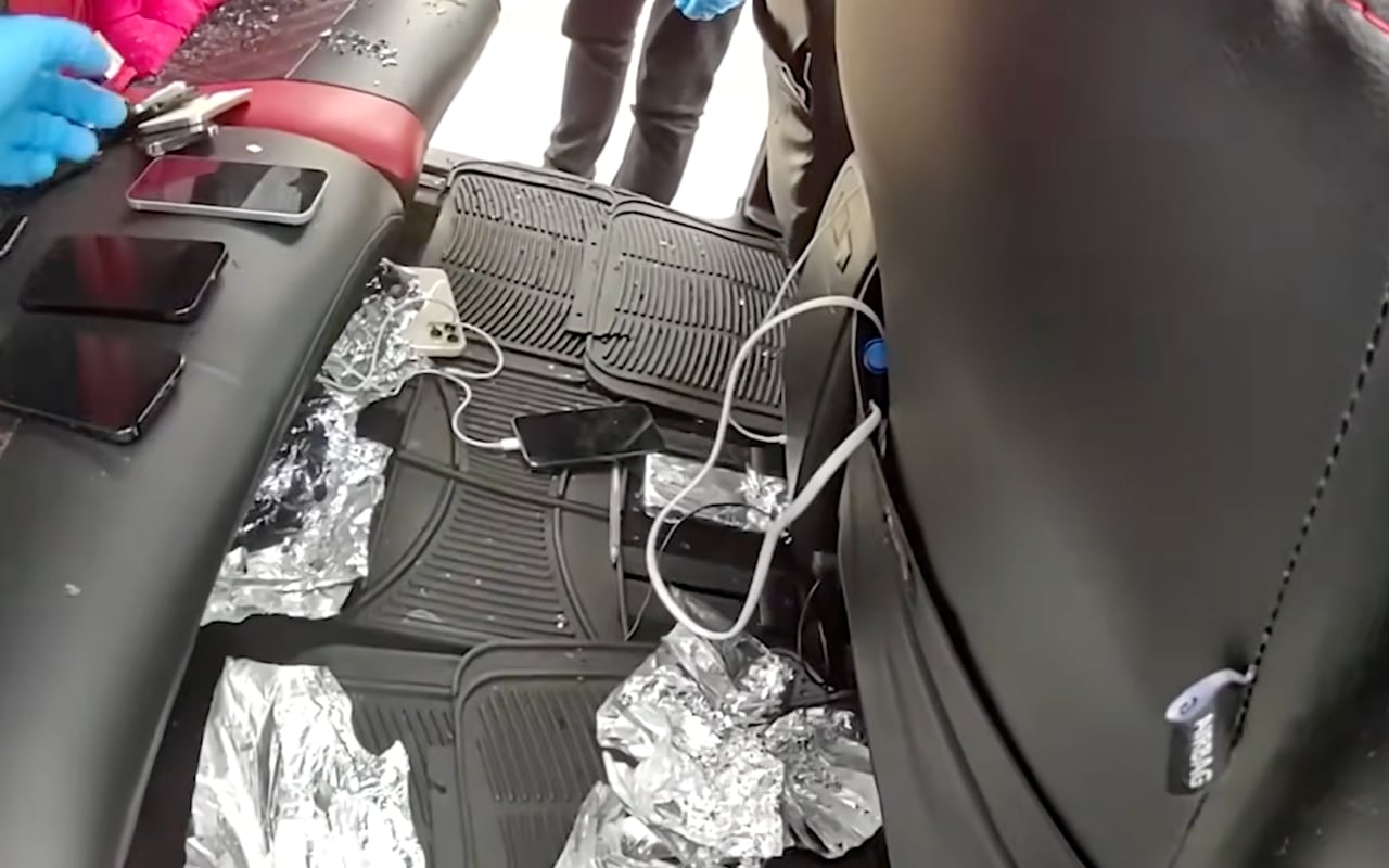 Pieces of aluminum foil are seen near suspected stolen phones in the back seat of a vehicle.