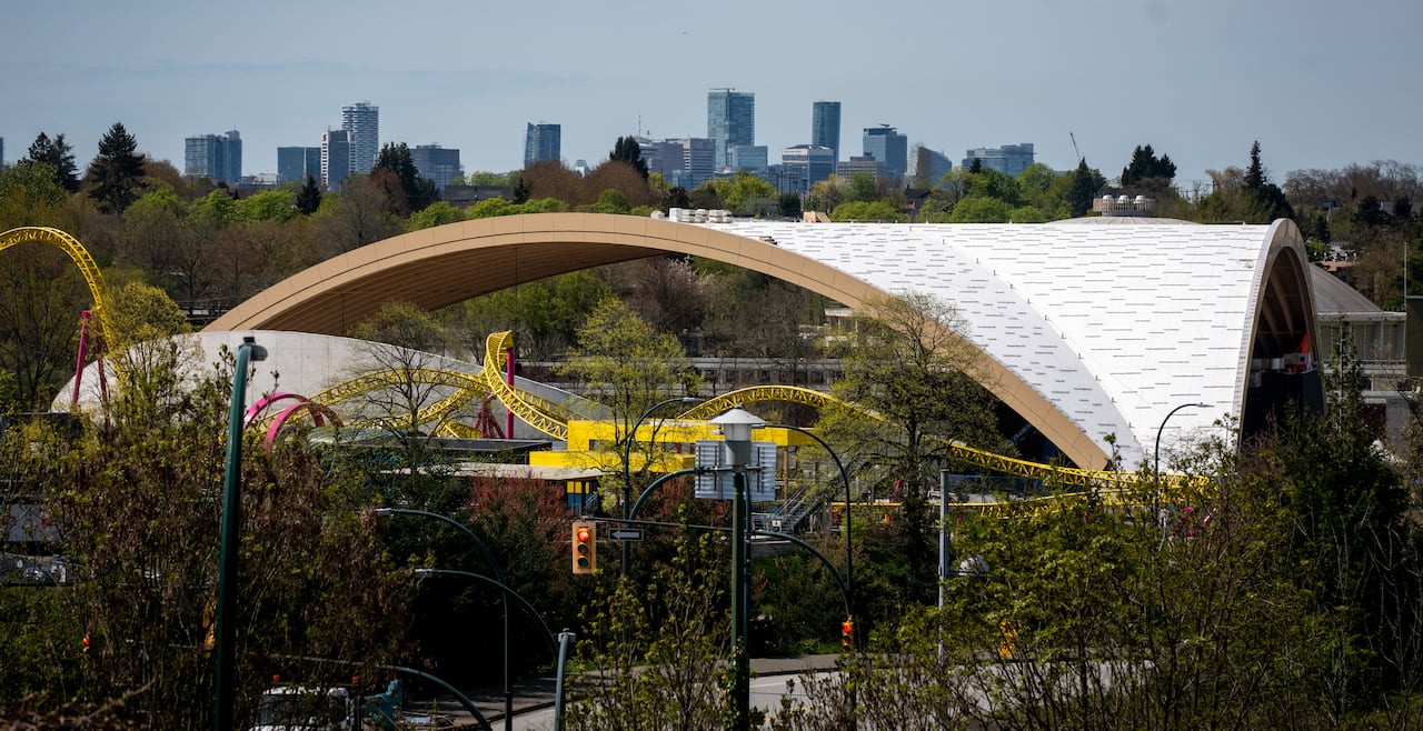 A large amphitheatre roof is seen with skyscrapers in the background.
