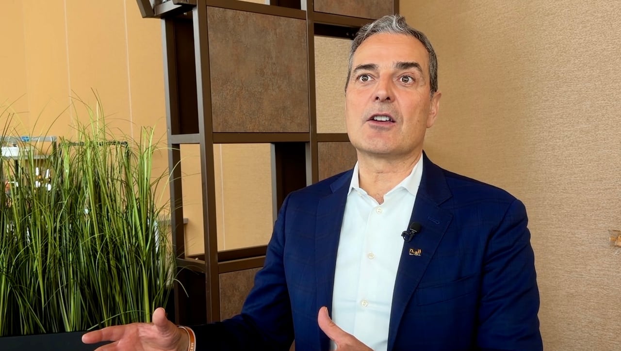 A man in a suit gestures with his hands while being interviewed.