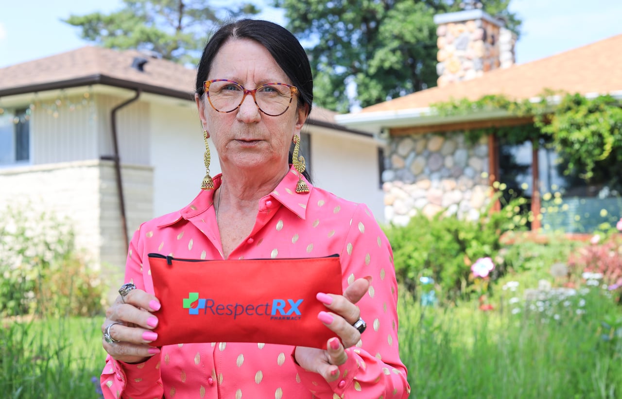 A woman in long black hair that is pulled back in a pony tail, holds up a small red zippered pouch