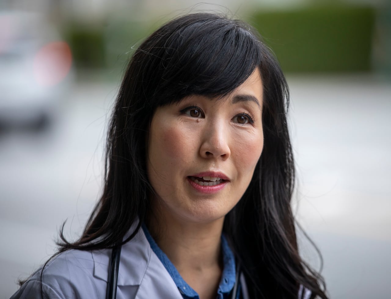 An East Asian woman speaks outdoors.