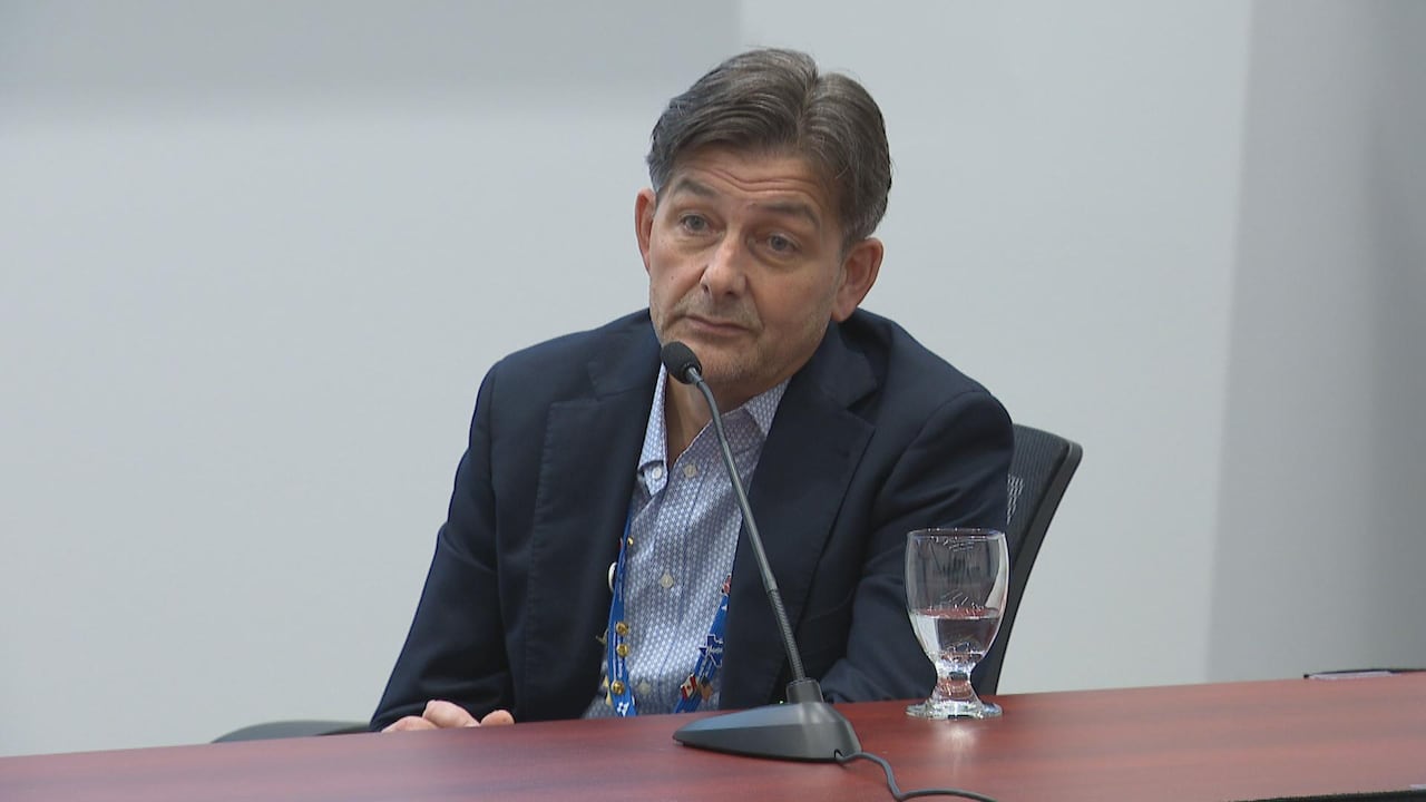 Man in blue suit, sitting down in front of mic.