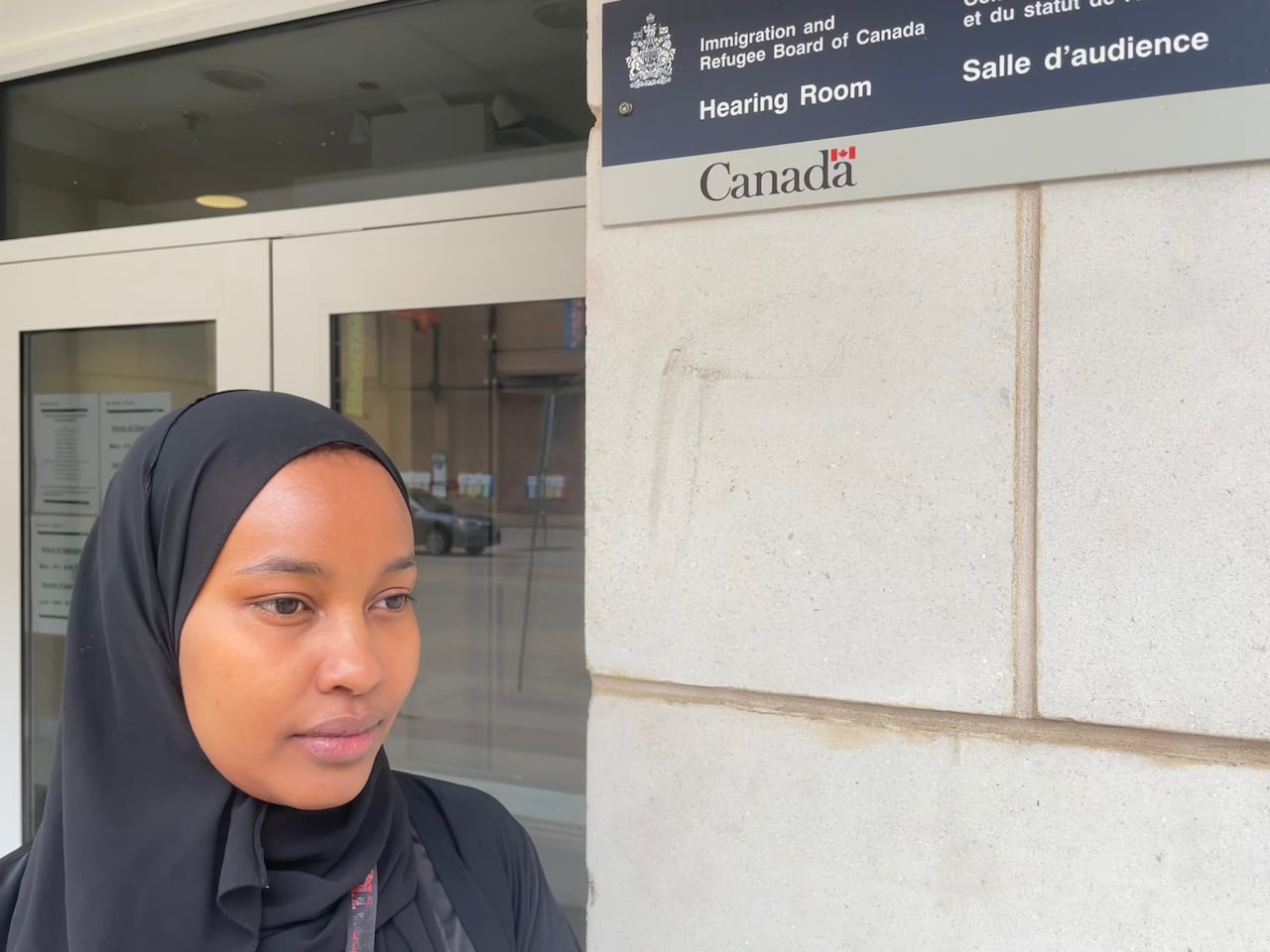 A woman stares off camera outside CBSA offices on 104th Street in Edmonton.