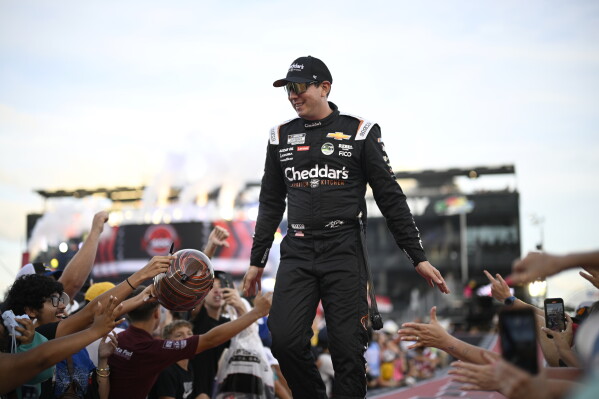 Kyle Busch interacts with spectators while walking down a runway during driver introductions before a NASCAR Cup Series auto race at Daytona International Speedway, Aug. 24, 2024, in Daytona Beach, Fla. (AP Photo/Phelan M. Ebenhack, File)