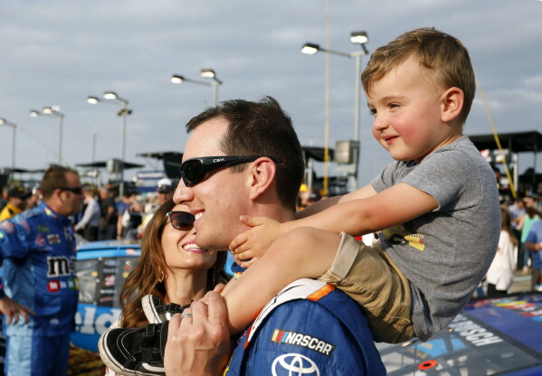 Kyle Busch carries his son, Brexton, as his wife, Samantha, left, watches before the NASCAR Cup Series auto race at Kansas Speedway in Kansas City, Kan., May 12, 2018. (AP Photo/Colin E. Braley, File)