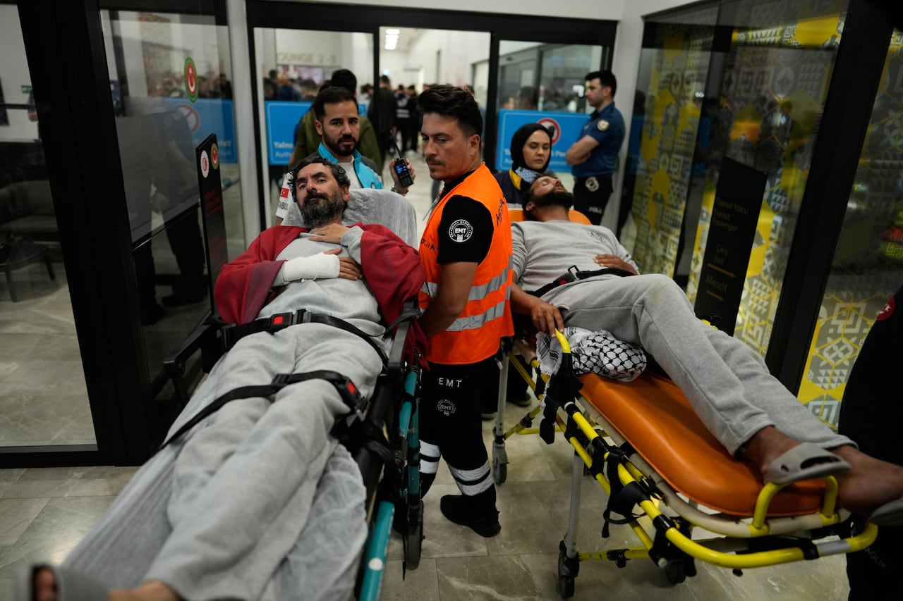Two men are wheeled out on stretchers.