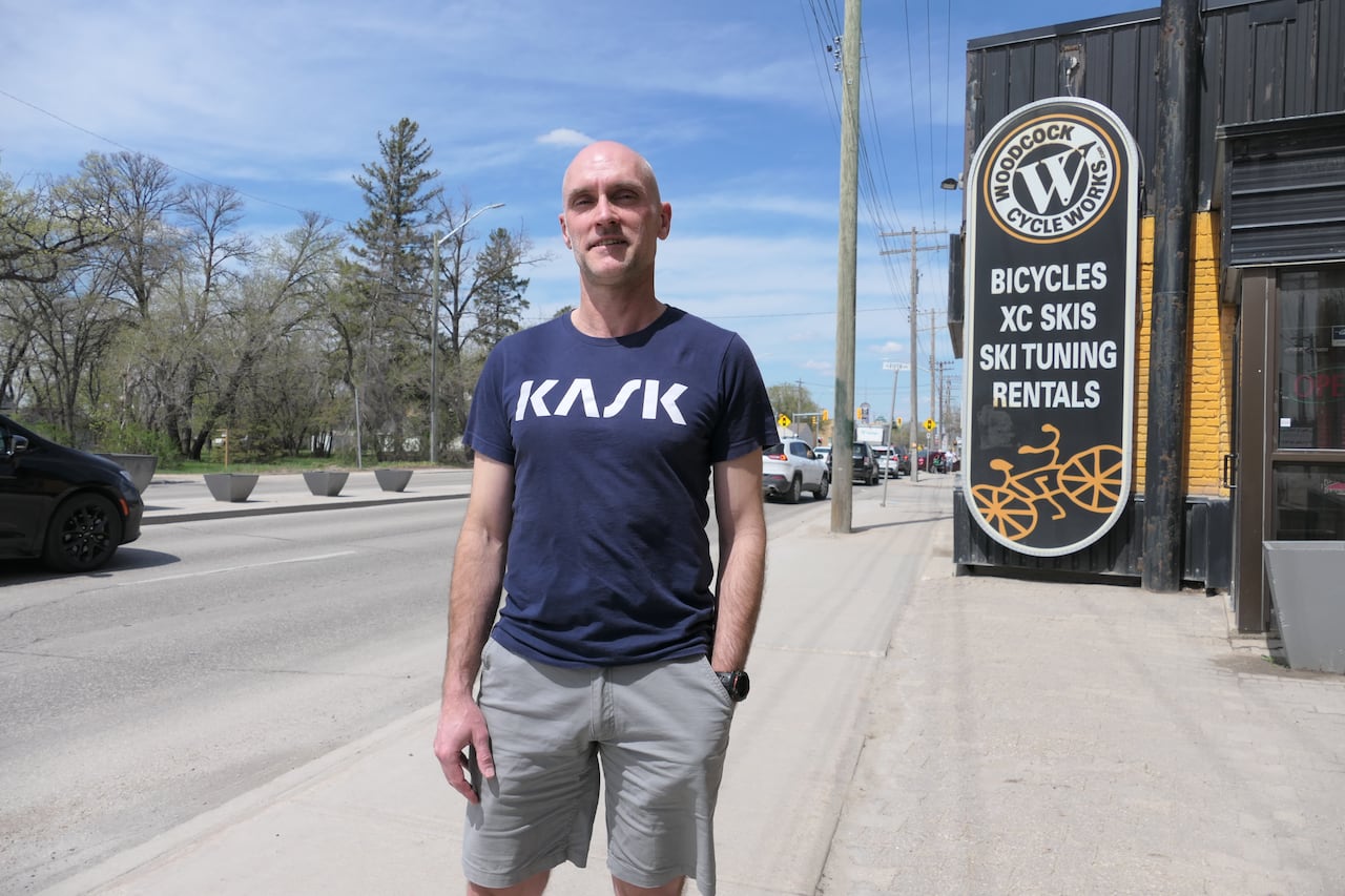 A man in a T-shirt and shorts stands outside a business.
