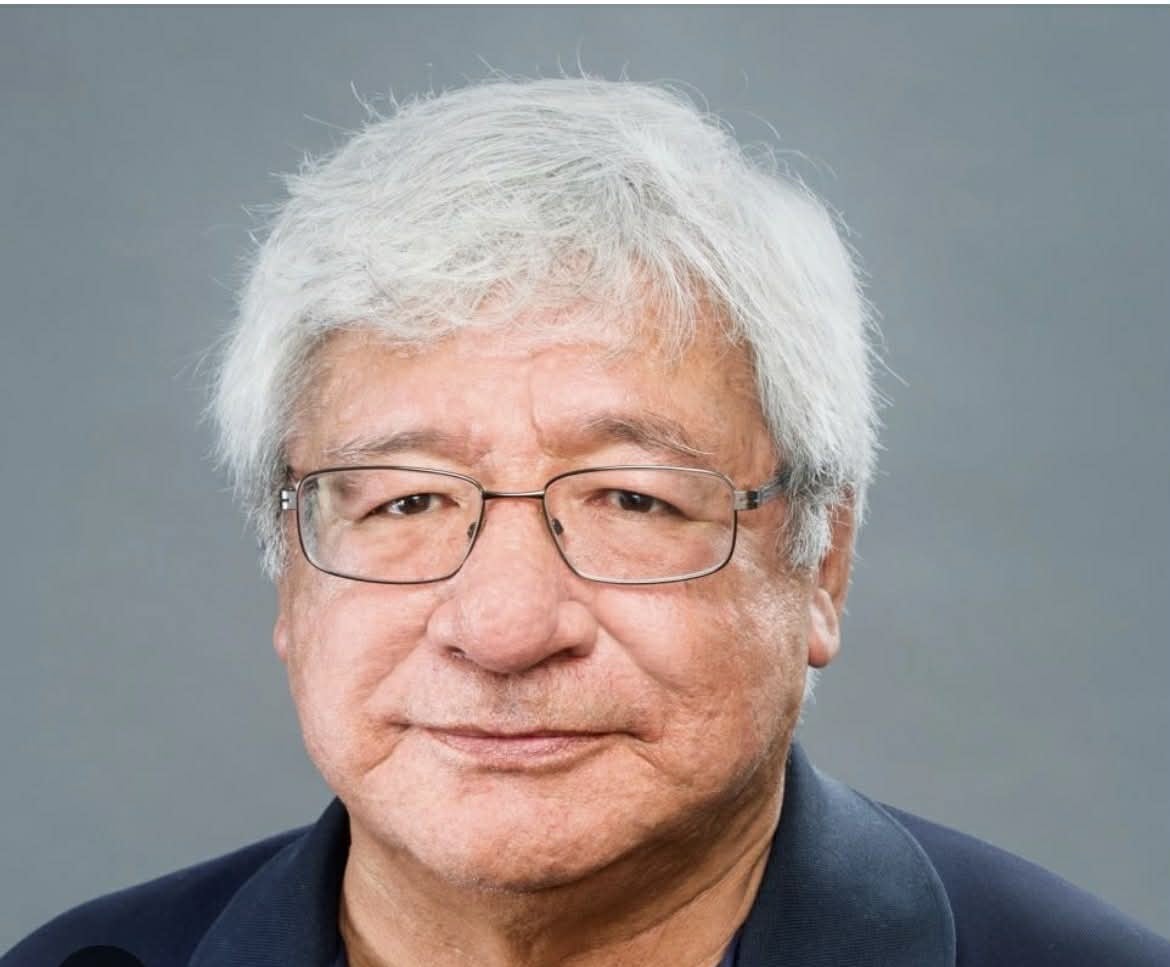 A white haired man with an unsmiling expression