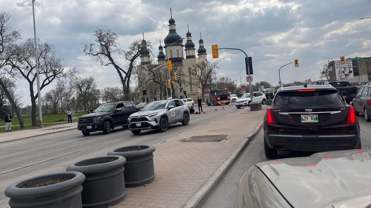 A line of cars at a city intersection, with a fire truck and pylons across the street