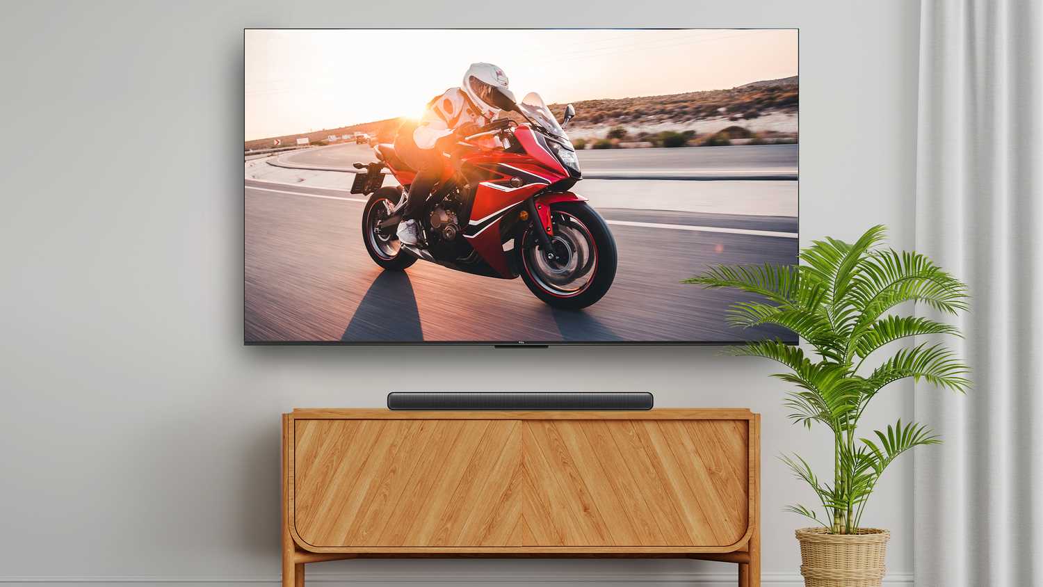 The TCL S45H soundbar on a table below a TV.
