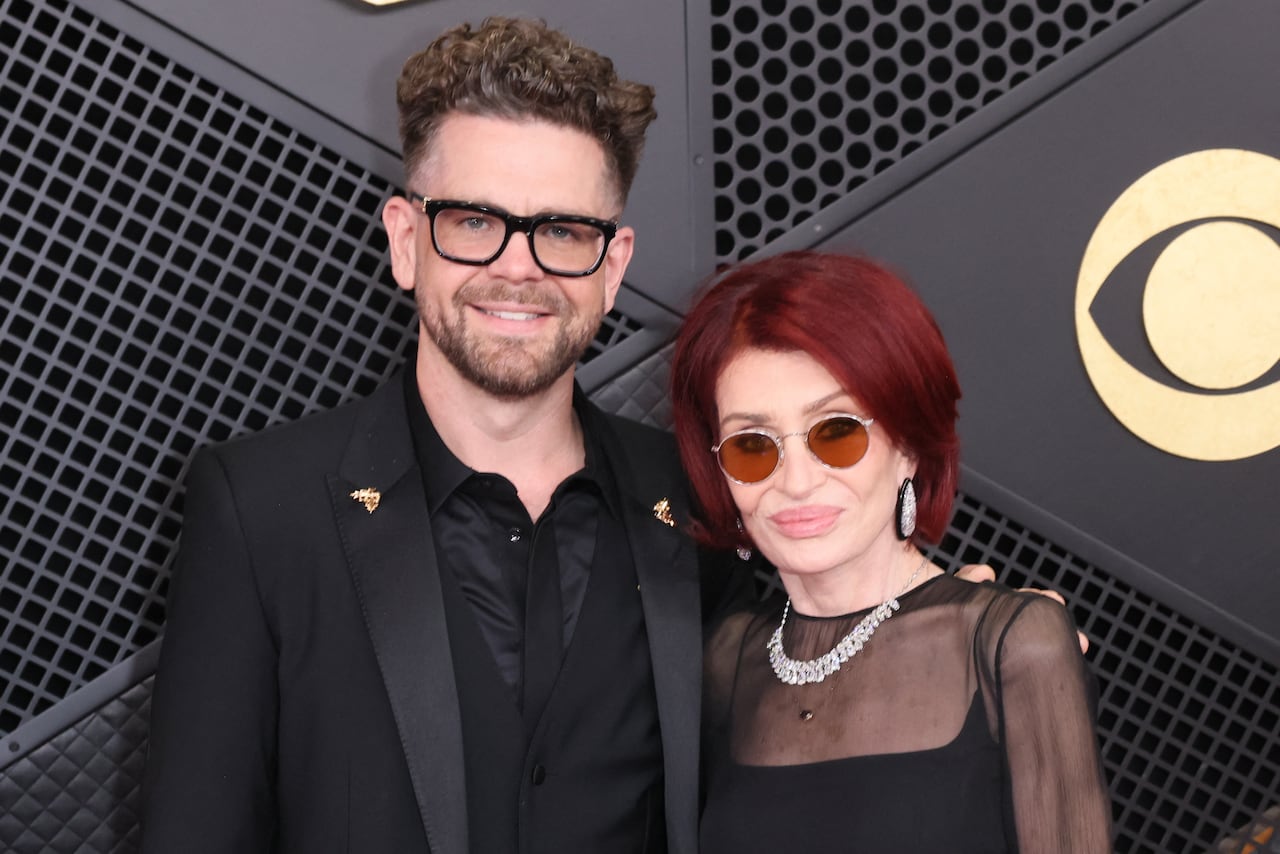 Man, Jack Osbourne and woman, Sharon Osbourne pose for a photo at the grammy awards in front of black backdrop