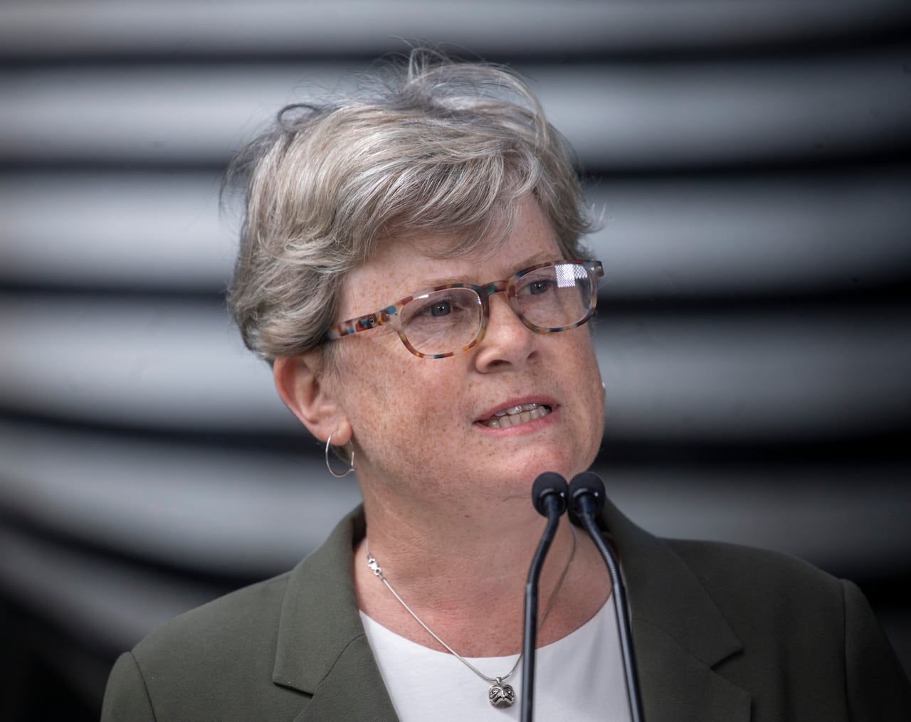 A white woman with short hair speaks into a mic.