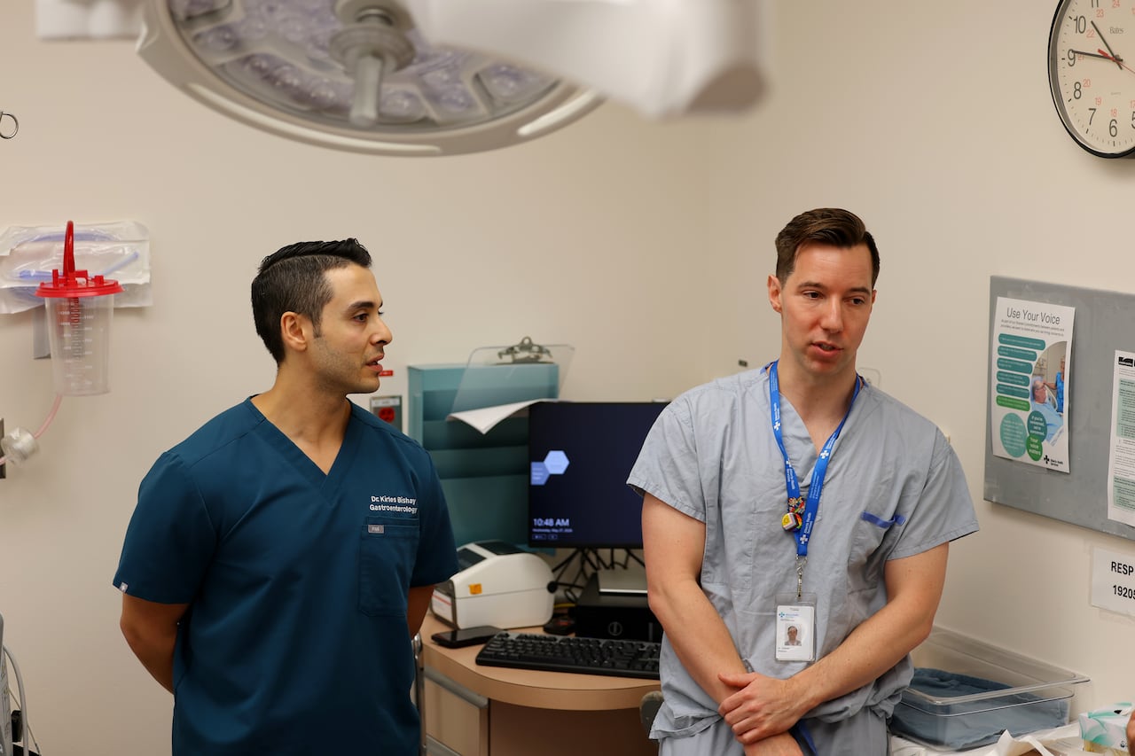 Two doctors speak to reporters at a hospital.