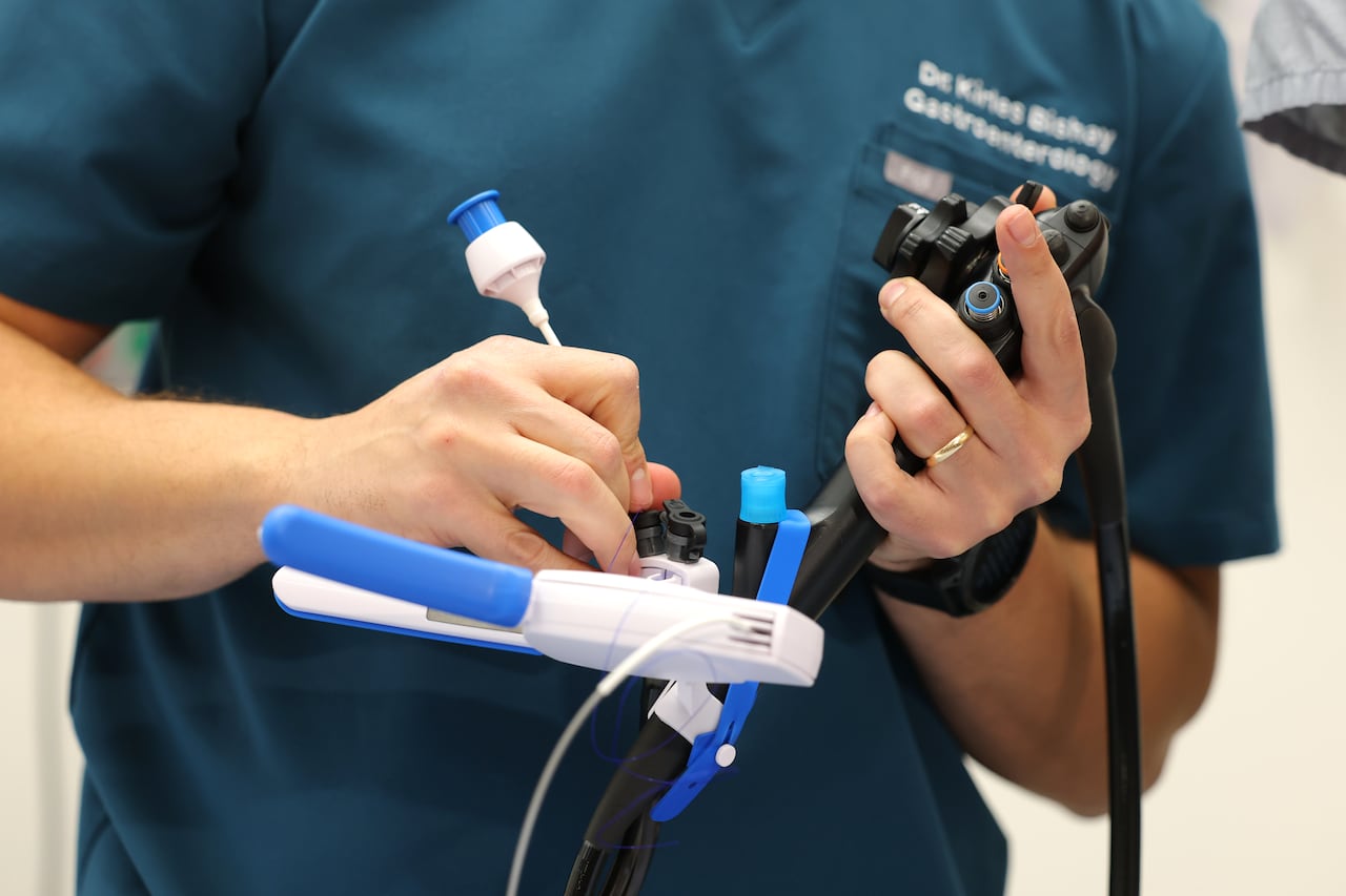 A doctor holds a piece of medical equipment in his hands.