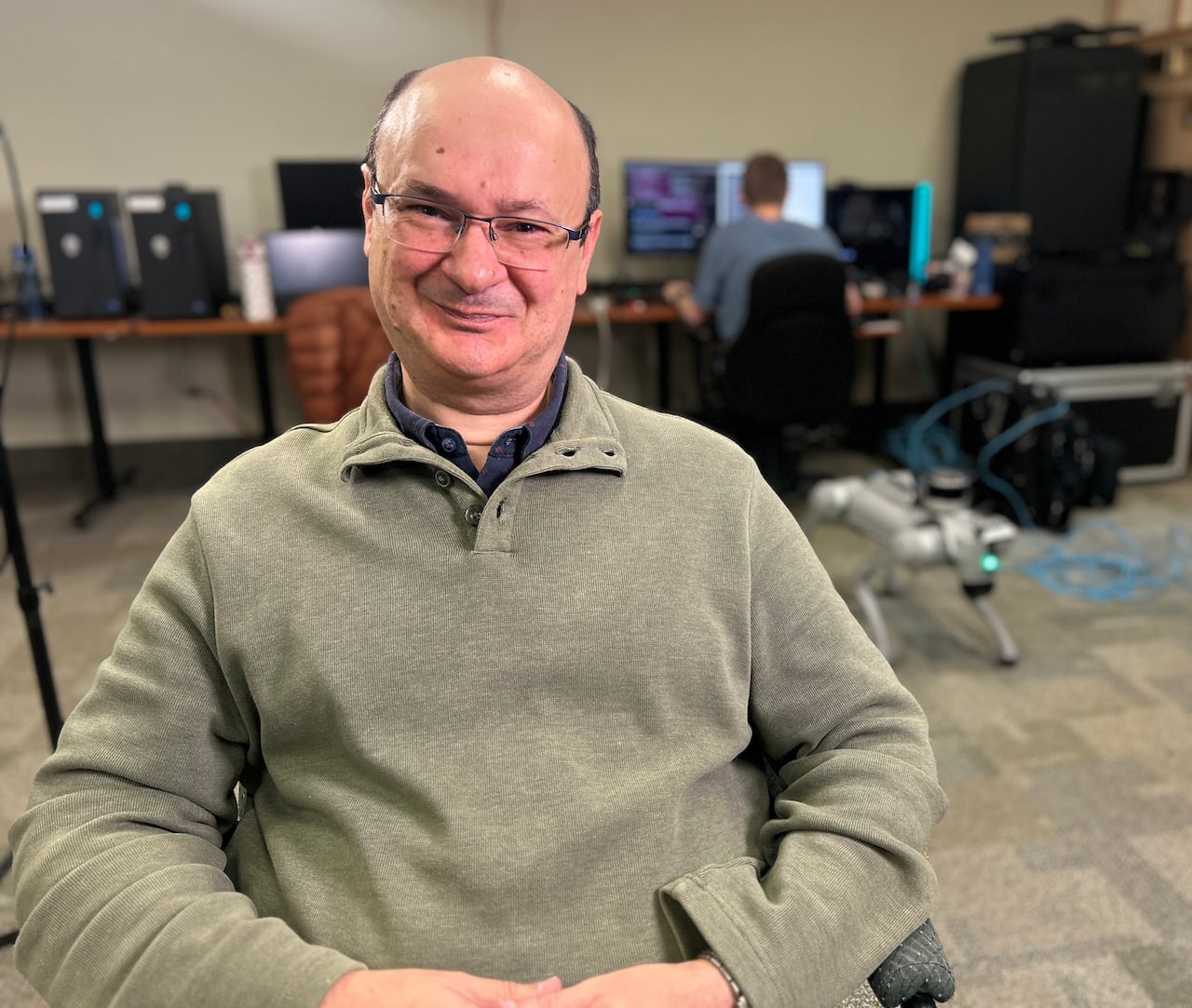 A man with glasses sitting in a computer lab.