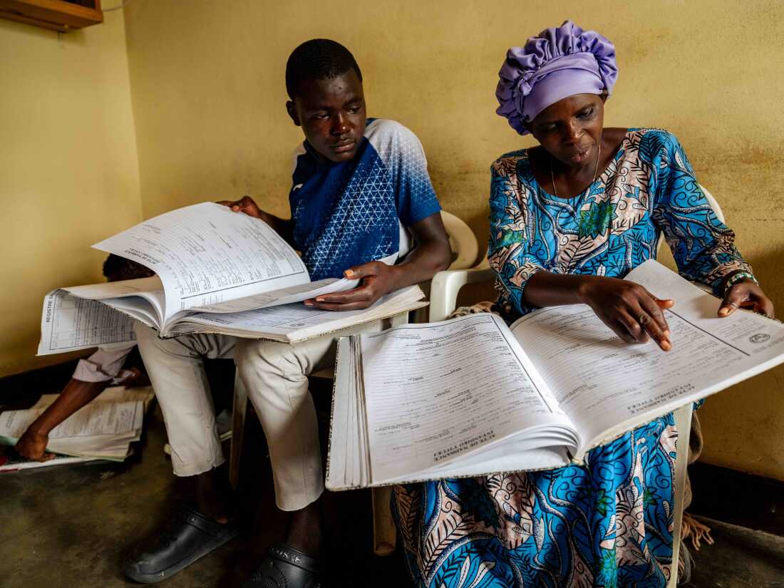 June 11, 2025. Musanze District, Rwanda. Goodlive Nyiramajyambere (left), Hosee Nziyonemeye (center), Icamdenien Uwamahoro (right), sort through the paper archives searching for birth and death registration of their relatives at the Civil Registration Office in Musanze District While Rwanda is actively digitizing all paper based civil records as part of a nationwide modernization effort, physical copies of original certificates are still required for some official procedures. The transition to digital systems aims to improve accessibility, reduce errors, and ensure more reliable documentation. Photo Credit: Juan Arredondo.