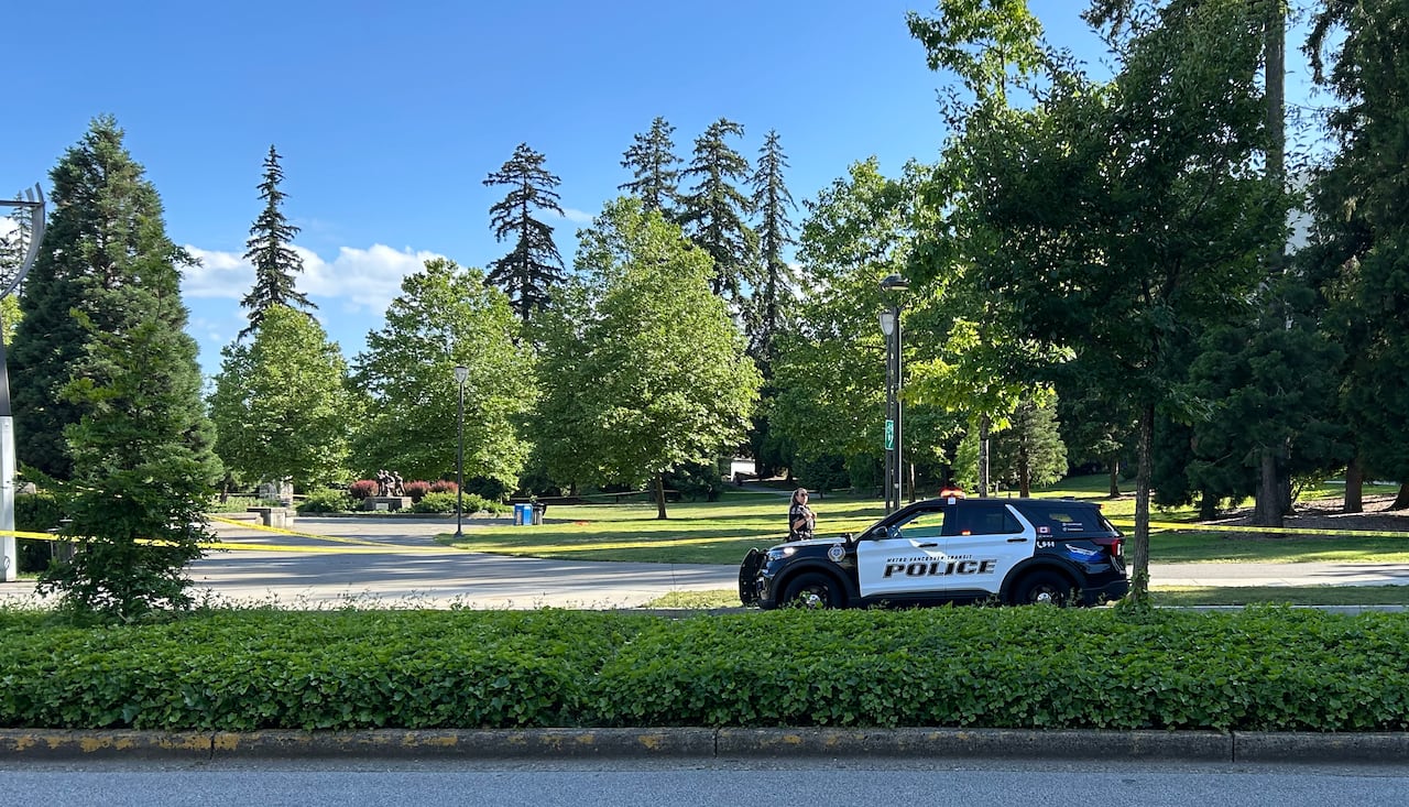 A police vehicle is seen along the side of a park on a sunny day.