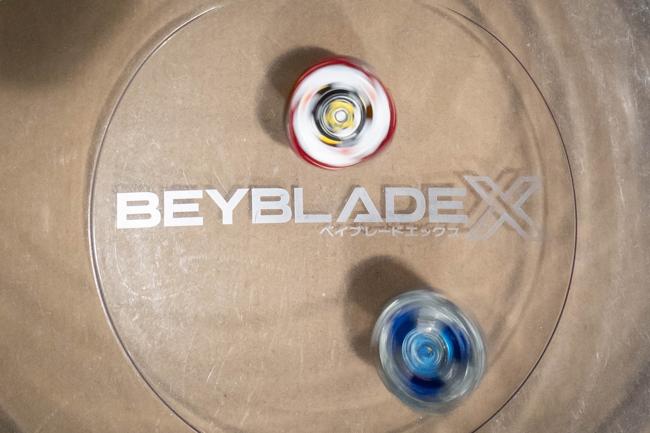 Two spinning tops are seen in a bowl marked 'Beyblade X'.