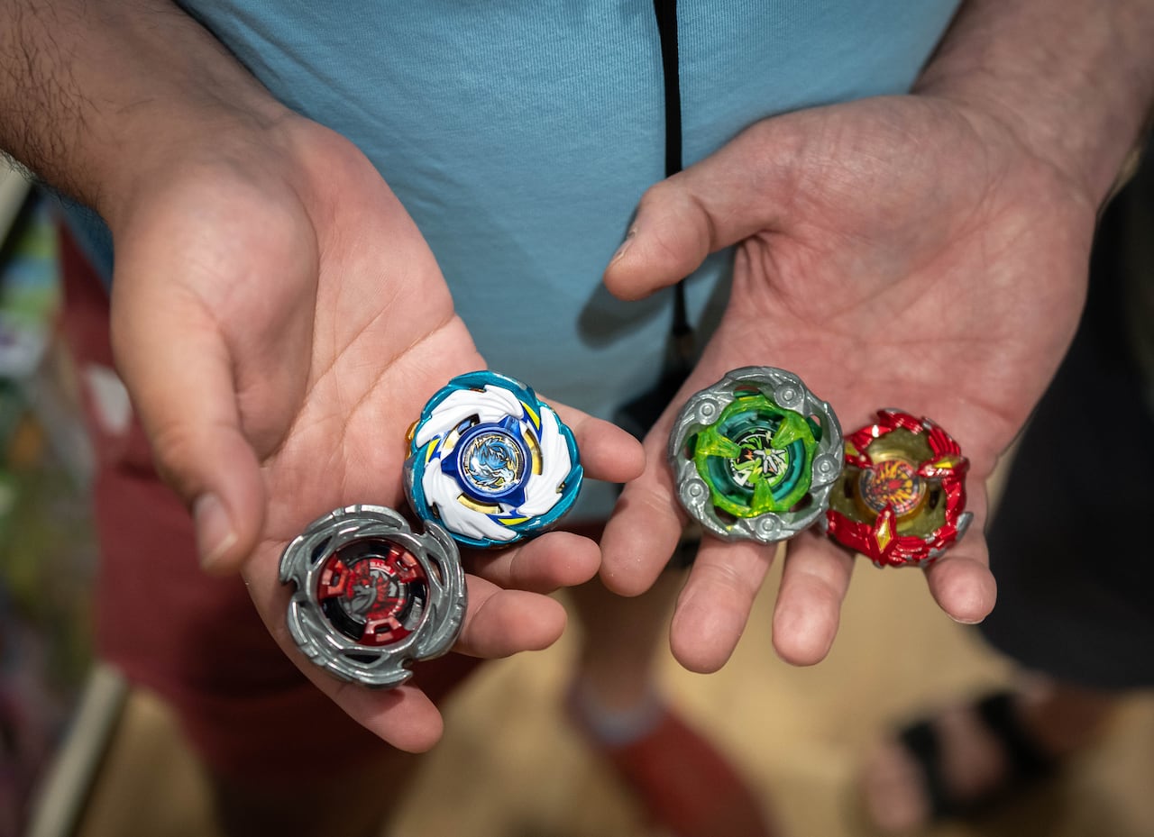 Two people hold colourful spinning toys in their palms.