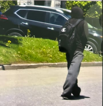 A person is seen from behind wearing a hoodie and carrying a backpack.