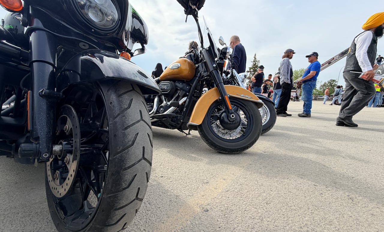 The front wheels of some motorcycles parked in an outdoor parking lot.