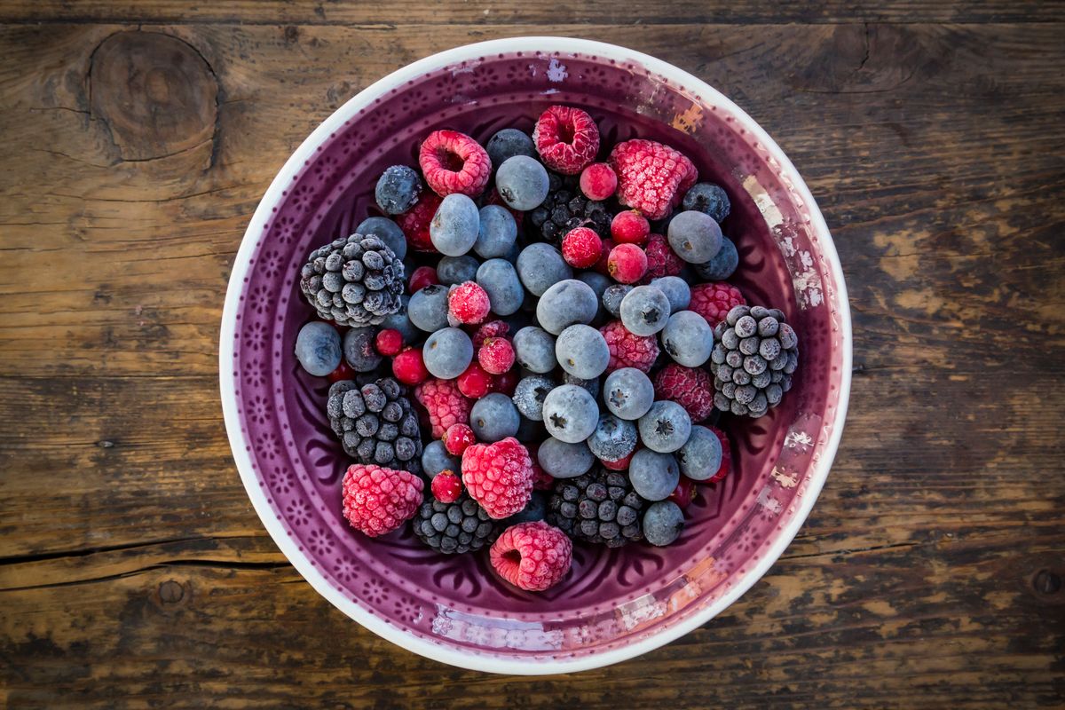 Different berries in a bowl on a wooden surface