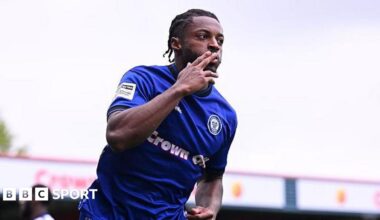 Rochdale's Devante Rodney celebrating scoring by kissing his index finger while wheeling away.