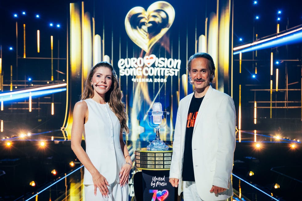 hosts at the eurovision song contest with a trophy and backdrop