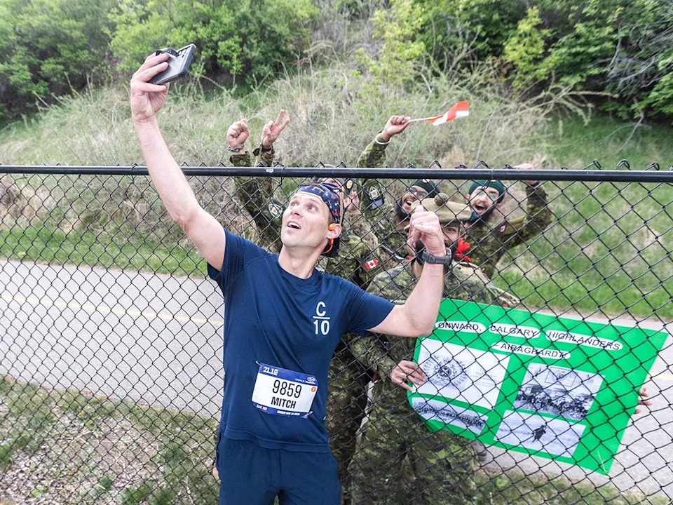 Mitch Walz takes a selfie with fellow members of the Calgary Highlanders who turned out to cheer him on as he finished the 21.1 km event of the Servus Calgary Marathon on Sunday, May 24, 2026.