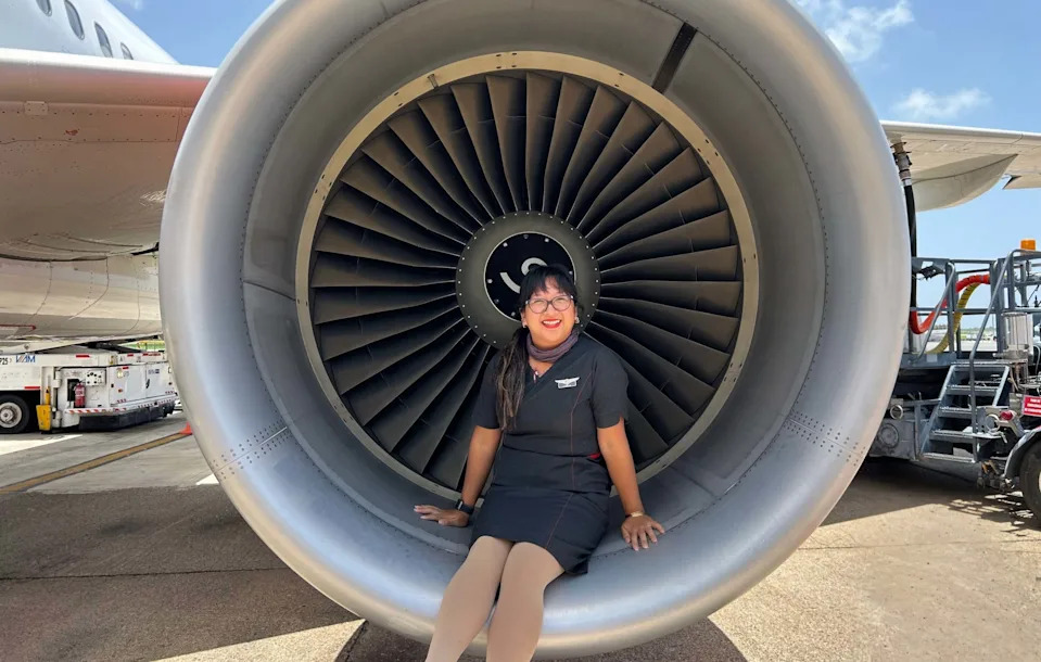 Pam Huynh, a flight attendant, sits on a jet engine of a plane.
