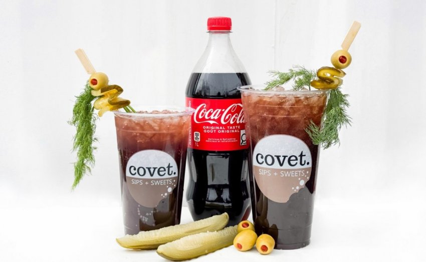 A Caesar cocktail made with Coca-Cola instead of clam tomato juice, served in a rimmed glass with festival garnishes at the Calgary Stampede.