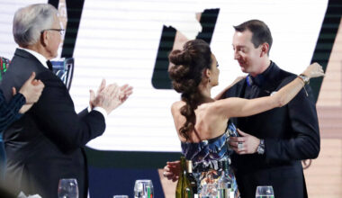 Kyle Busch, right, is hugged by his wife, Samantha, and applauded by team owner Joe Gibbs, left ...